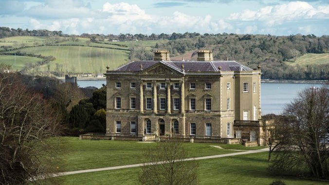 View of the Palladian-style side of Castle Ward house, with Strangford Lough and rolling hills beyond.
